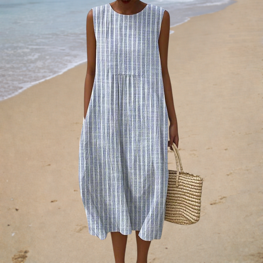 Women's blue and white striped sleeveless midi dress on a beach