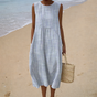 Women's blue and white striped sleeveless midi dress on a beach