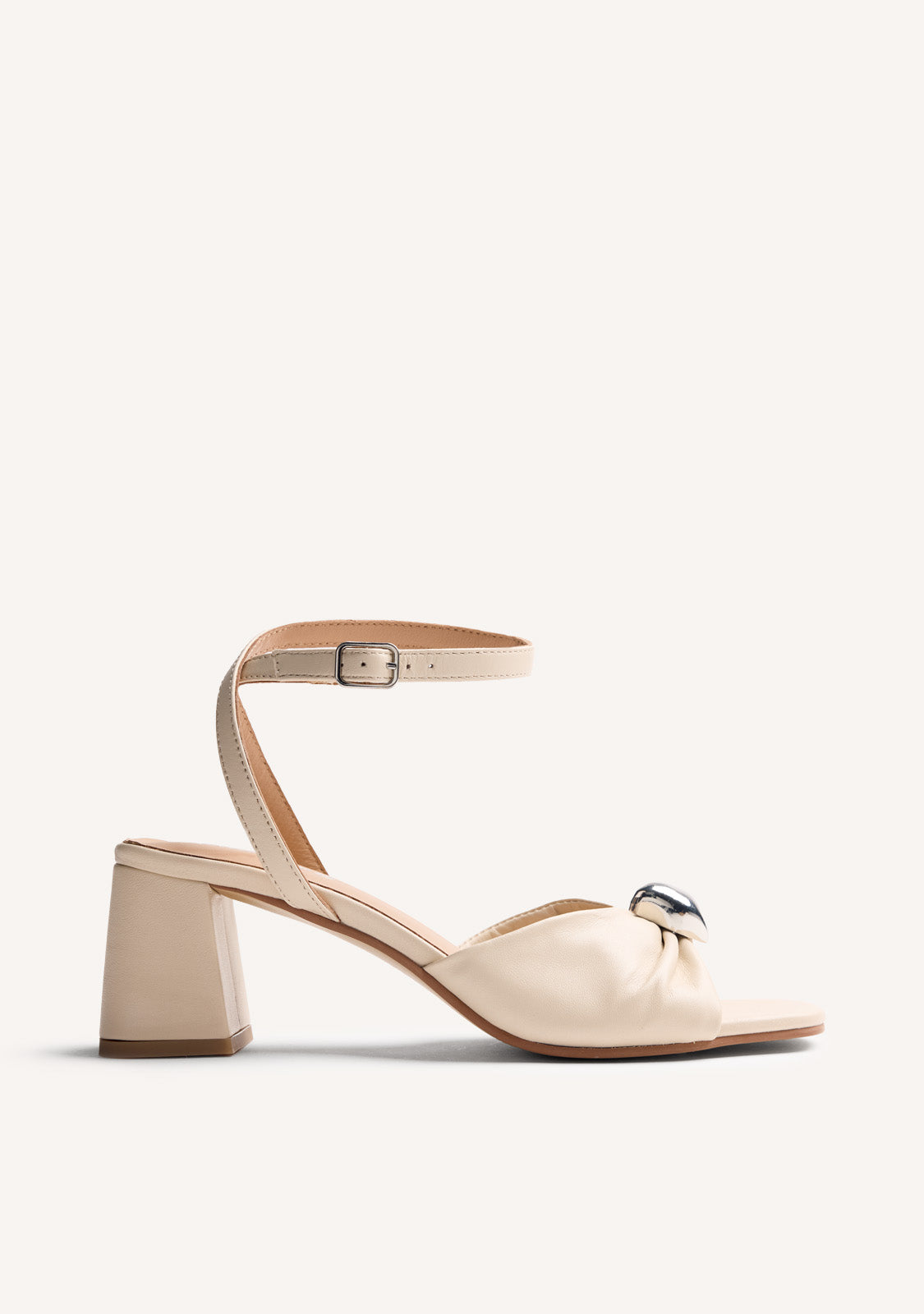 Beige women's heeled sandals with bow detail, silver-tone ornament and ankle buckle strap
