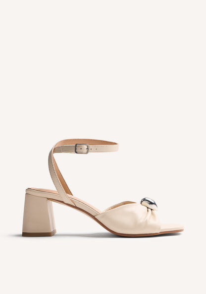 Beige women's heeled sandals with bow detail, silver-tone ornament and ankle buckle strap